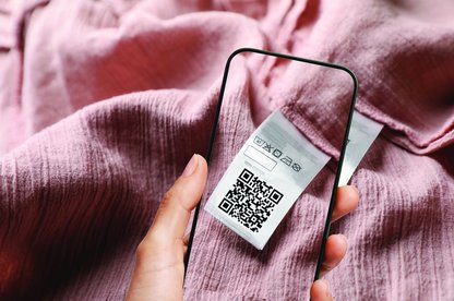 Handyscreen über Textilie mit Bild des QR-Codes auf der rosafarbenen Textilie