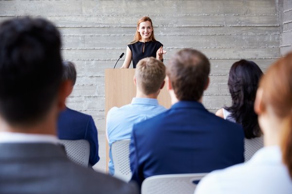 Frau hält Experten-Vortrag vor einem Publikum