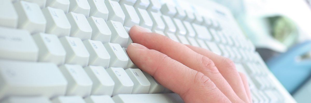 Hand tippt auf weißer Computertastatur.
